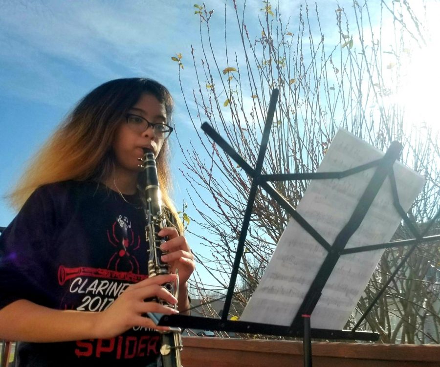 Staff writer and clarinetist Mikaela Ramirez (senior) plays the provided piece, Simple Gifts for the Lift Your Voice event. The sounds of music ring faintly through the neighborhood as others participate.