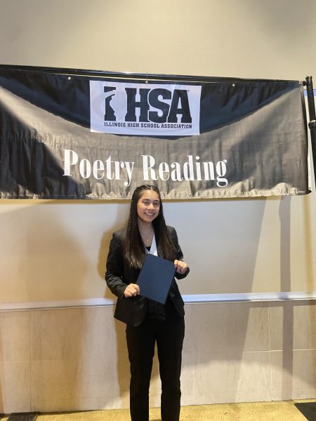 Plainfield East High School junior, Stella Abarca, at Sectionals for Speech Team on Feb. 10, as she poses by the Poetry Reading sign.