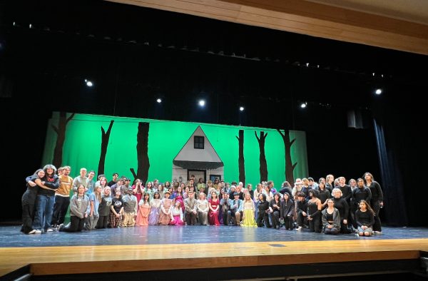 Cast, crew, and pit gathered around a prop for a group photo after an in school performance on Wed. 13, 2024 