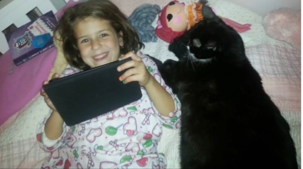 Mia+Graske+at+age+5%2C+relaxing+with+her+iPad+and+cat%2C+Zip.+